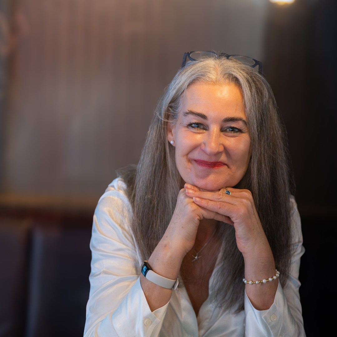 Jacqueline Carson smiling warmly at the camera in a white blouse